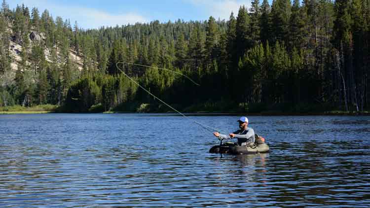 A man fly fishing from a fishing float tube in open water on a lake.