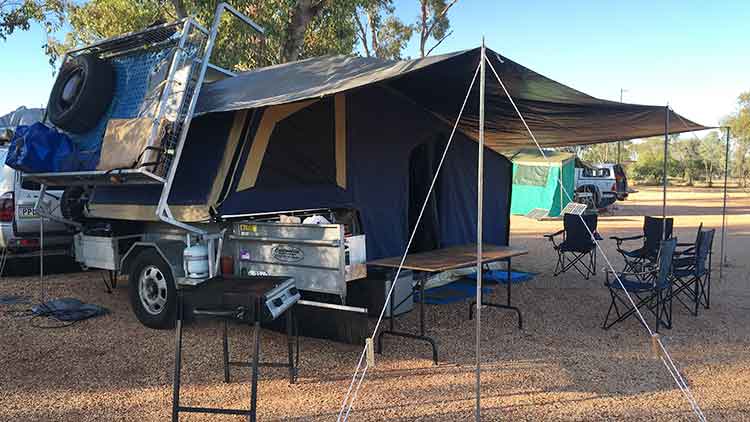 Camper trailer set up with expanded tent and overhang at a campground.