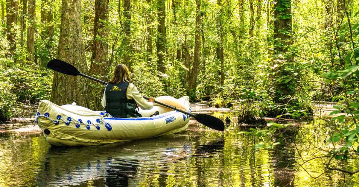 Female kayaker kayaking in an inflatable kayak through a beautiful swamp.