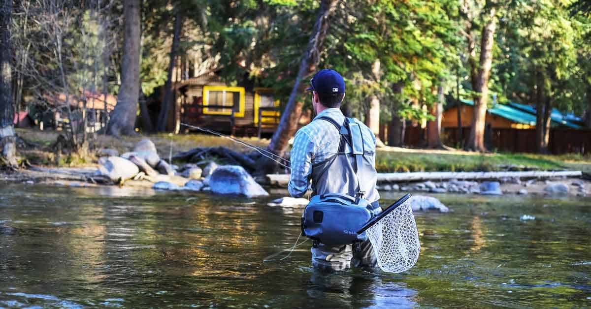 Fly fisherman wearing waders in a river while fishing.