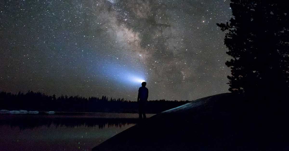 An outdoorsman using a headlamp to find his way on an outdoor adventure after dark.