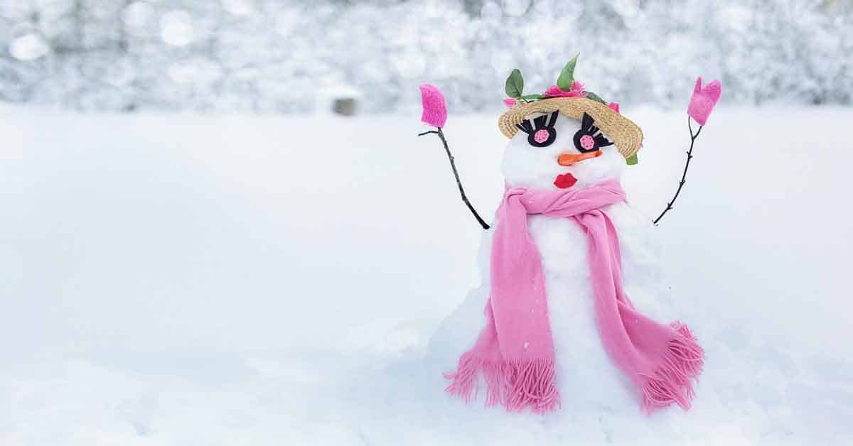 A snowman or rather snowwoman with a flowery hat with pink roses, pink eyes, eyelashes, carrot nose, red lips, pink mittens, and pink scarf.