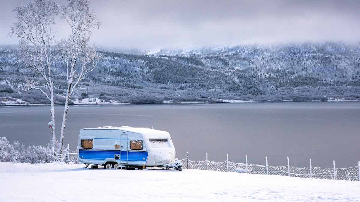 Camper set up at a lake on a snowy winter day.