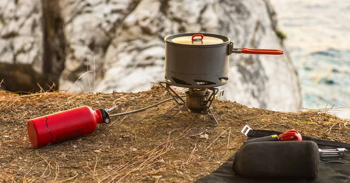 Liquid fuel (white gas) camping stove set up for cooking on a cliff overlooking the ocean in winter.
