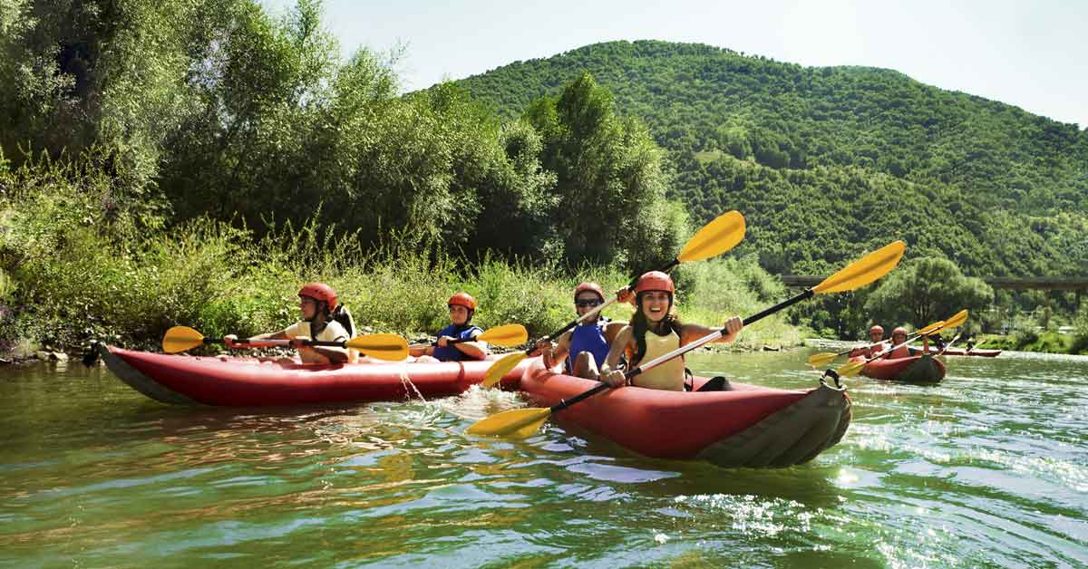 Kayakers paddling on a river in modern, durable, inflatable kayaks.