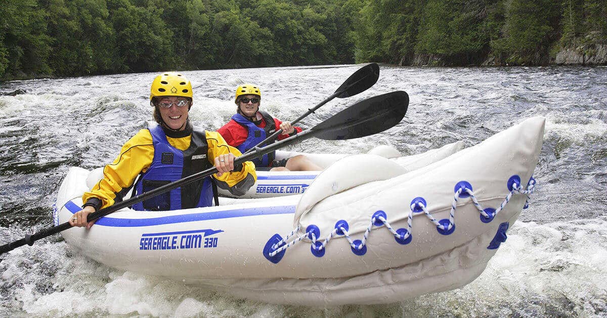 Two kayakers solo paddle on a whitewater river in Sea Eagle 330 Sport Inflatable Kayaks.