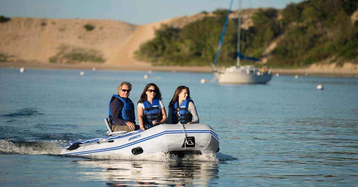 The Sea Eagle 10’6″ Sport Runabout Inflatable Boat with three people cruising along in a bay.
