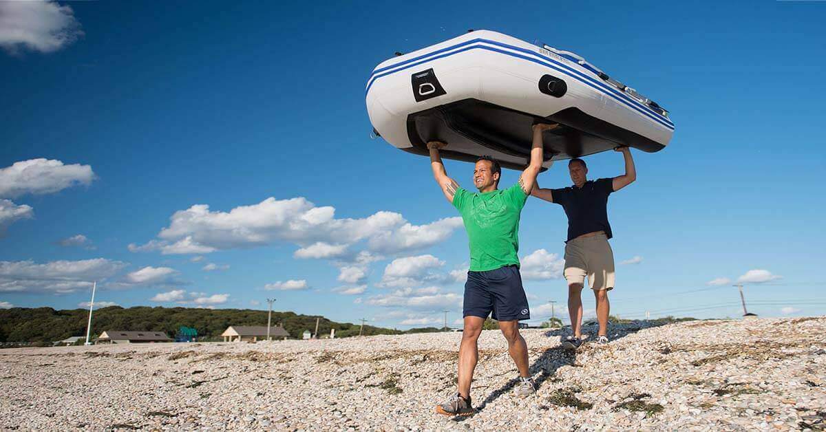Two guys carrying a Sea Eagle 10’6″ Sport Runabout Inflatable Boat above their heads to the put-in.