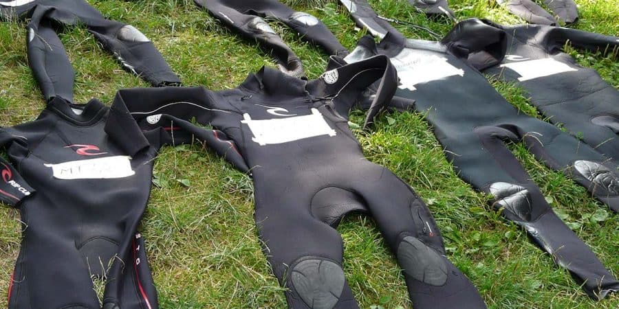 Wetsuits laying out in the grass for a triathlon.