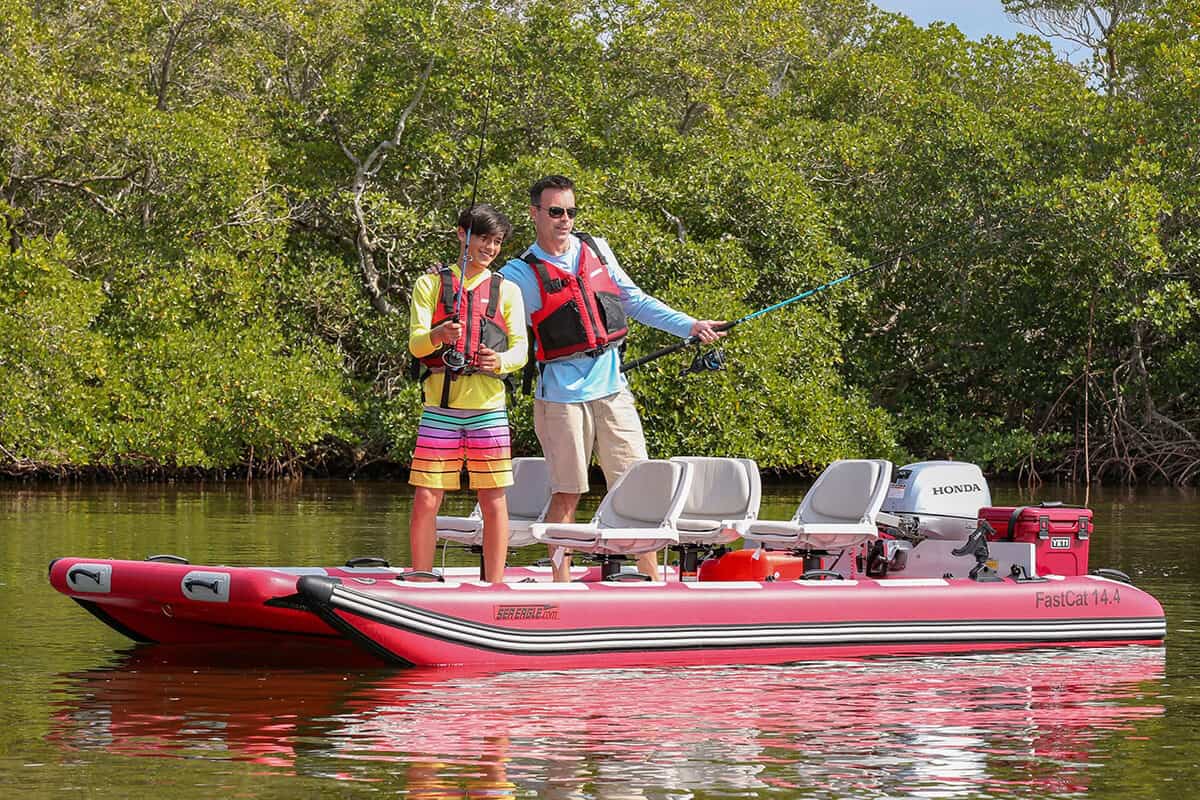 A father and son standing and fishing from a Sea Eagle FastCat14 Catamaran Inflatable Boat.