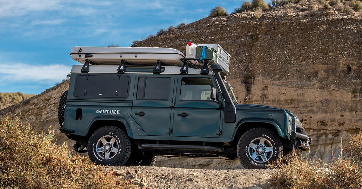 A hard shell roof-top tent on top of a vehicle out in the desert.