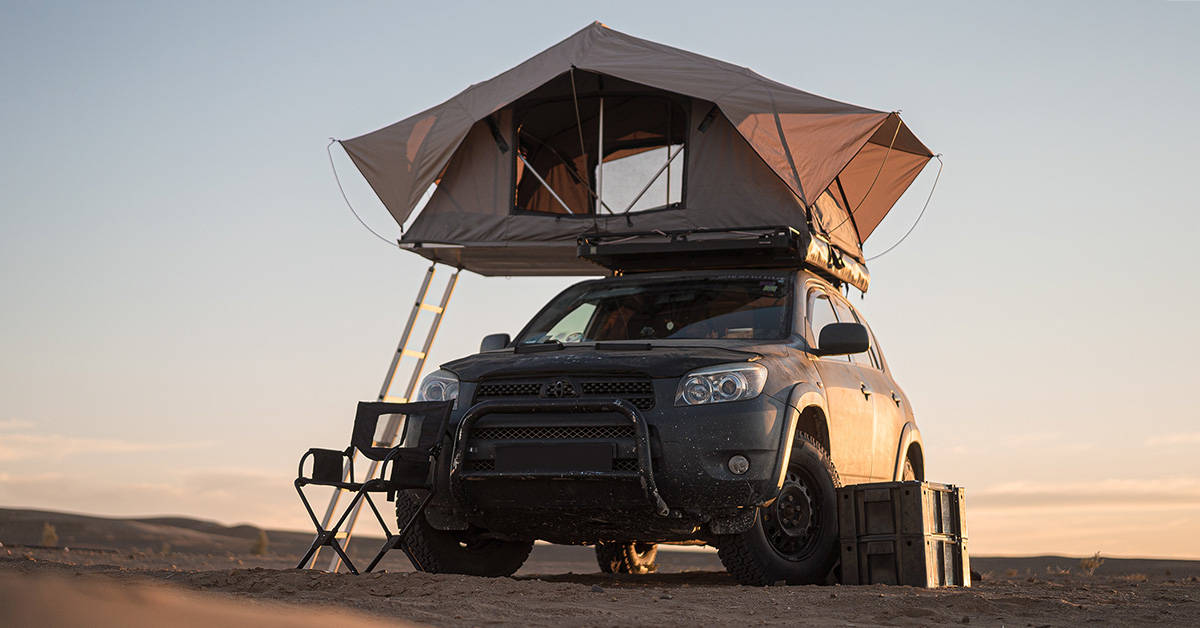 A soft shell rooftop tent on a car in the desert.