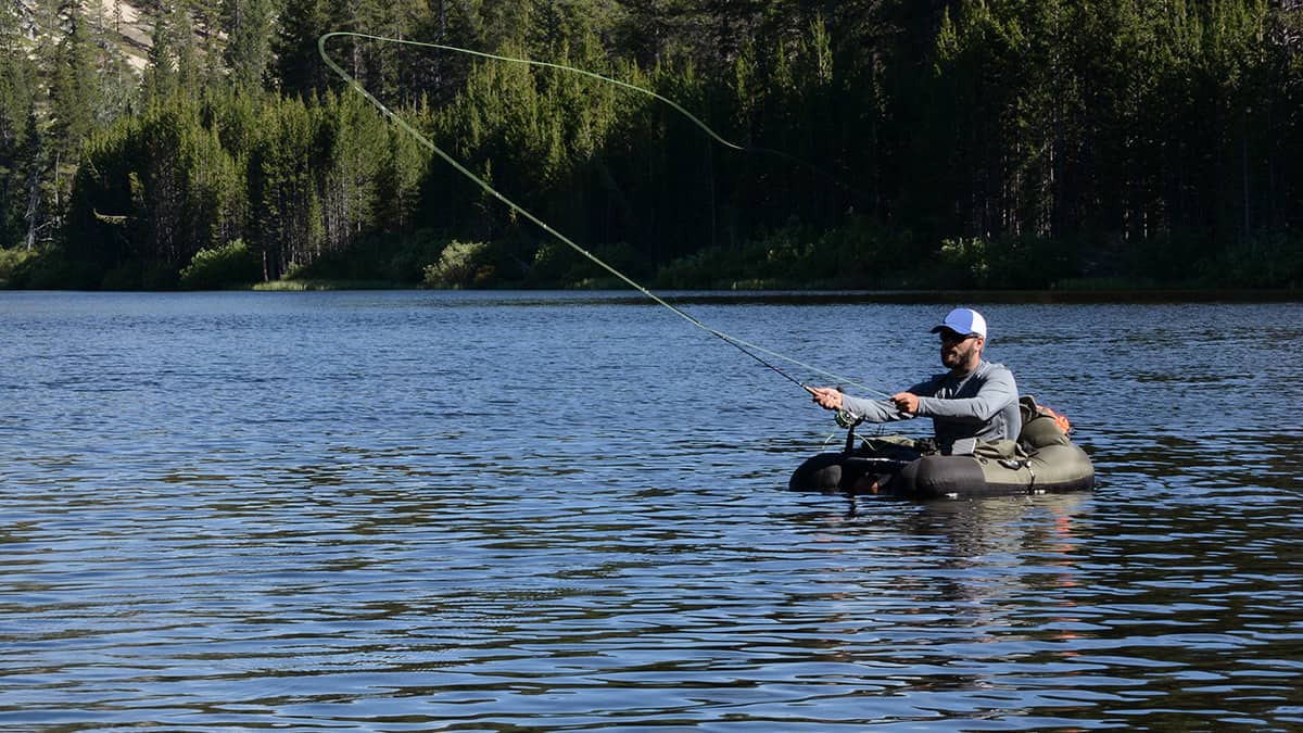 A man fly fishing from a fishing float tube in open water on a lake.