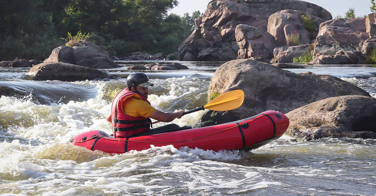 A man packrafting in a packraft on a whitewater river.