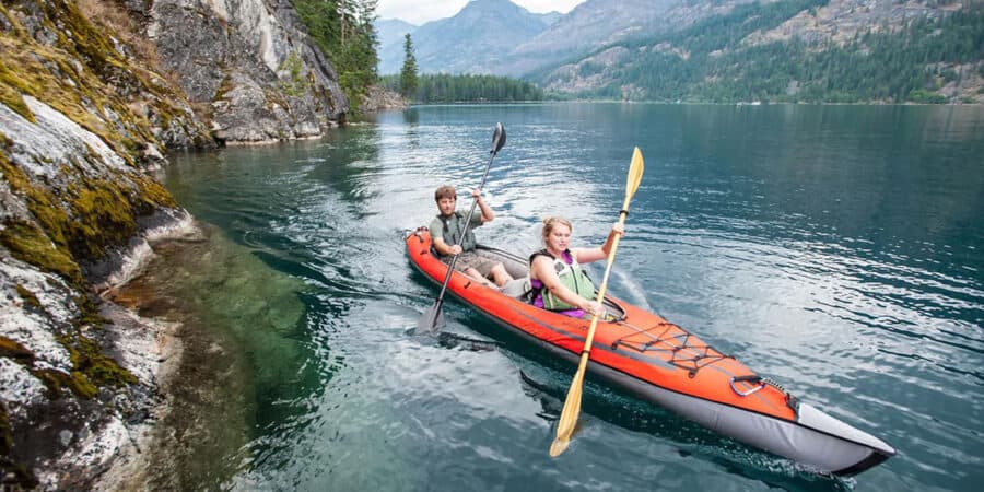 Two kayakers paddling an Advanced Elements AdvancedFrame Convertible Elite Inflatable Kayak on a mountain lake.
