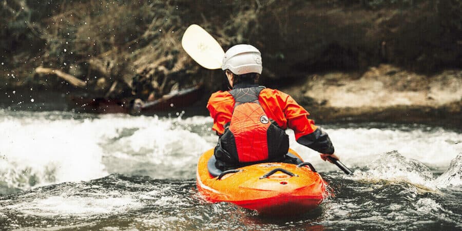 Kayaker keeping warm in frigid water temperatures by wearing a drysuit.