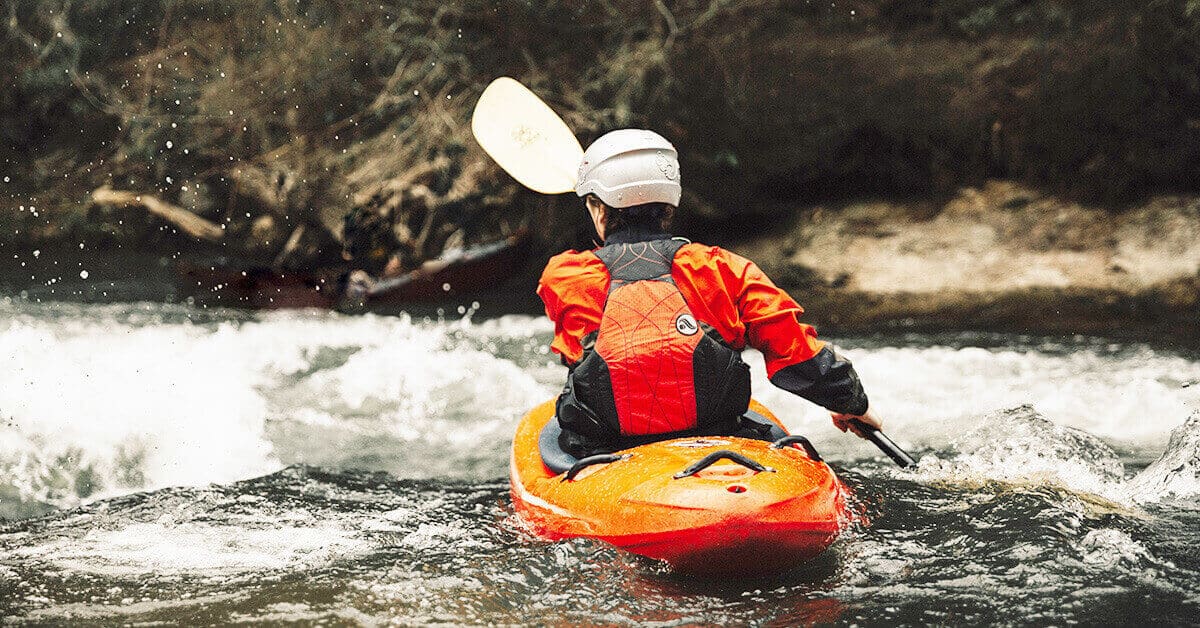 Kayaker keeping warm in frigid water temperatures by wearing a drysuit.