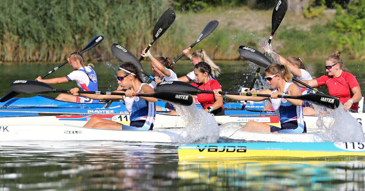 A group of female kayakers racing in a river kayaking competition.