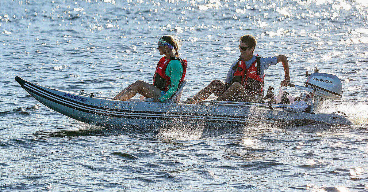 Two people in a Sea Eagle 437ps PaddleSki Inflatable Tandem Catamaran-Kayak-Boat with a Honda outboard motor.
