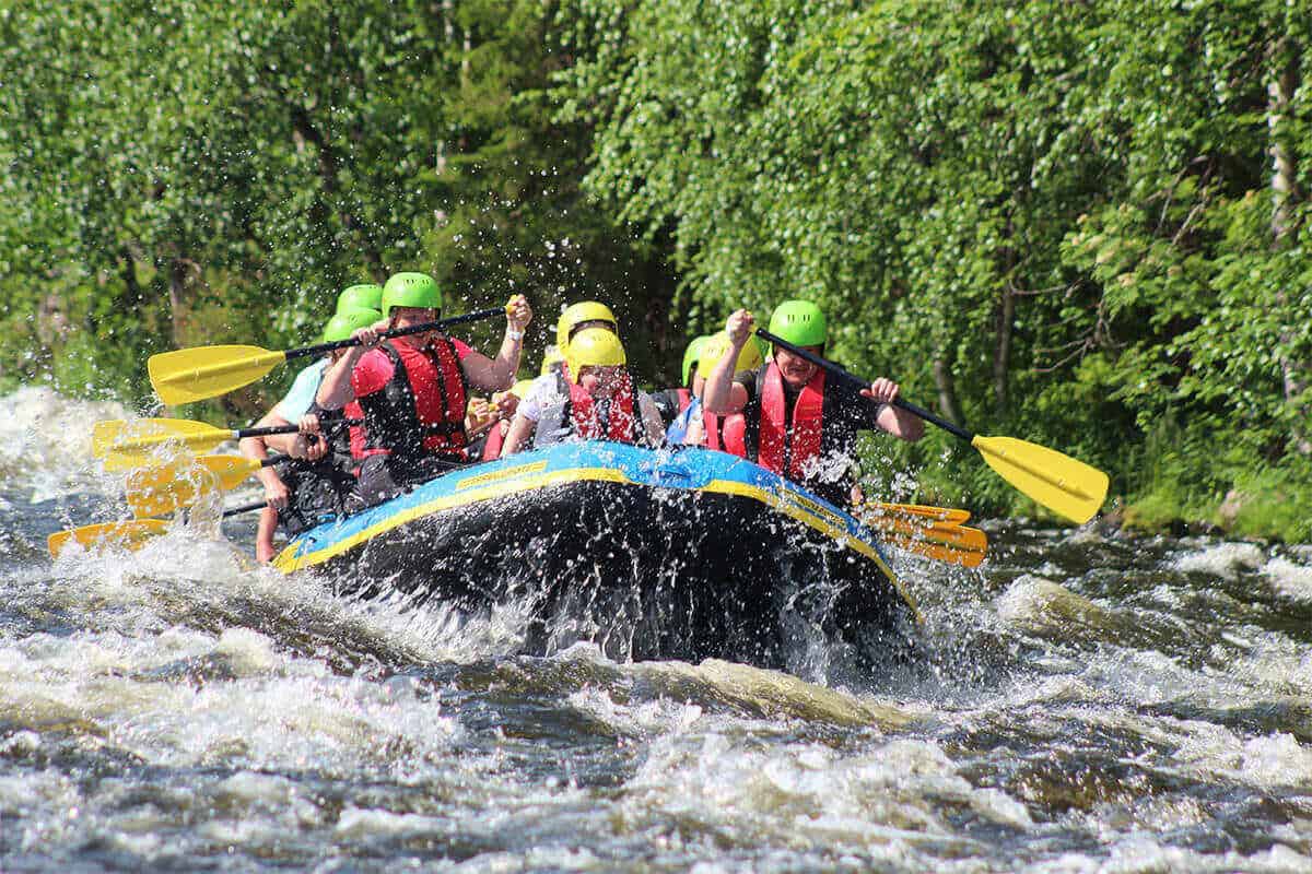 A group of people wearing PFDs rafting on a whitewater river.