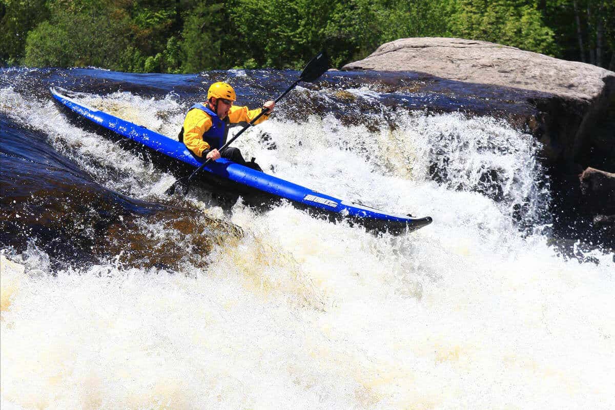 A kayaker solo paddling on a whitewater river in a Sea Eagle 380x kayak.