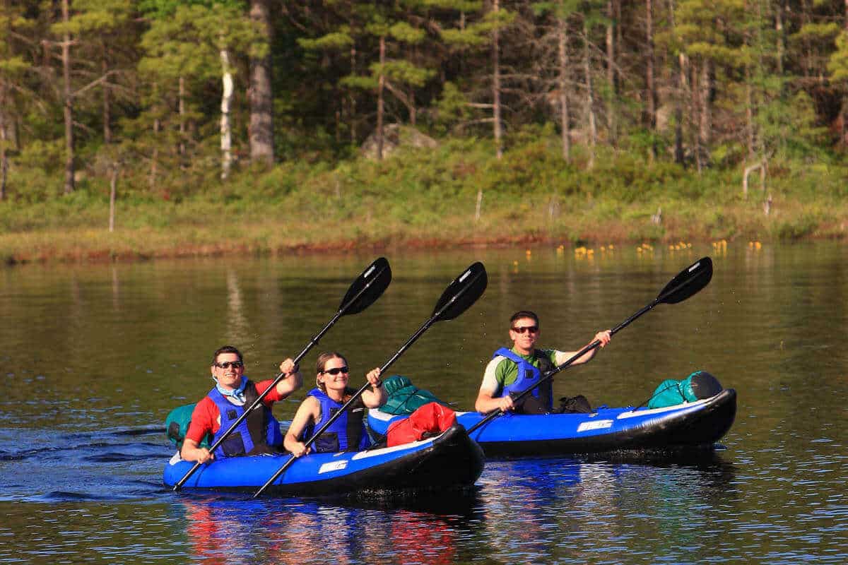 A group of kayakers paddle Sea Eagle 380x Explorer kayaks packed with camping gear.