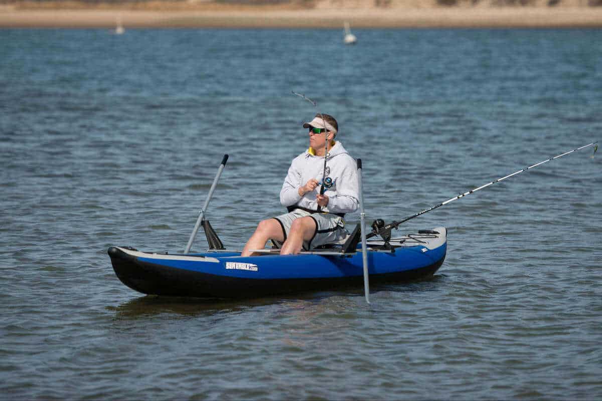 A boater fishing from a Sea Eagle 380x Explorer outfitted with a rowing kit and fishing gear.