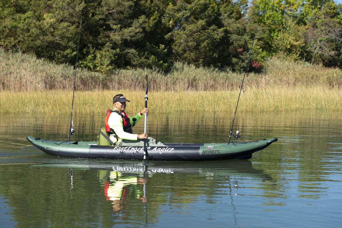 A fisherman paddles a FastTrack 385fta on a still lake.