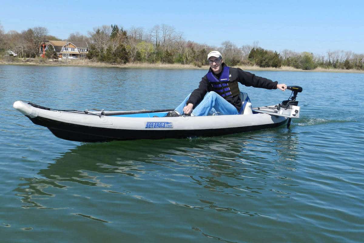 A boater in a Sea Eagle 385ft FastTrack with a trolling motor glides across a lake.