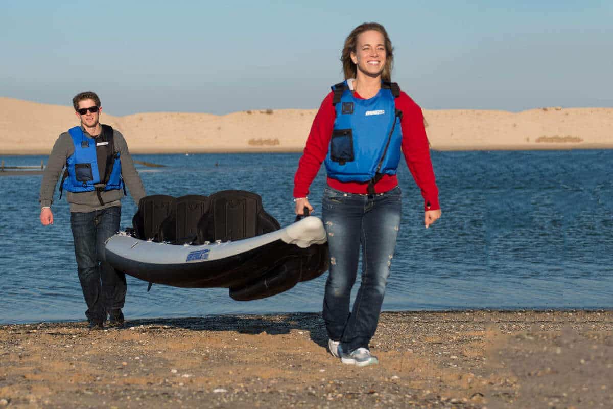 Two boaters carrying a 3-person 465 FastTrack from a lake where they were kayaking.