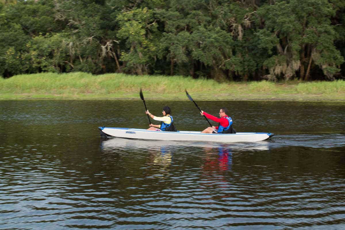 Two kayakers tandem paddling a Sea Eagle 473rl RazorLite on a lake.