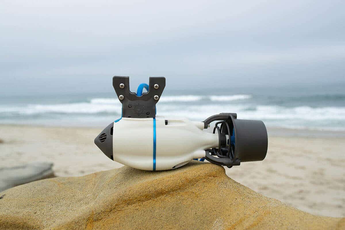 A Bixpy motor for a small personal boat showcased on a rock on an ocean shoreline.
