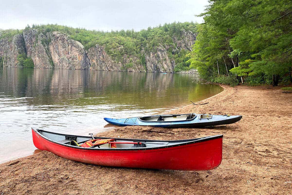 A canoe and kayak on the beach of a lake.