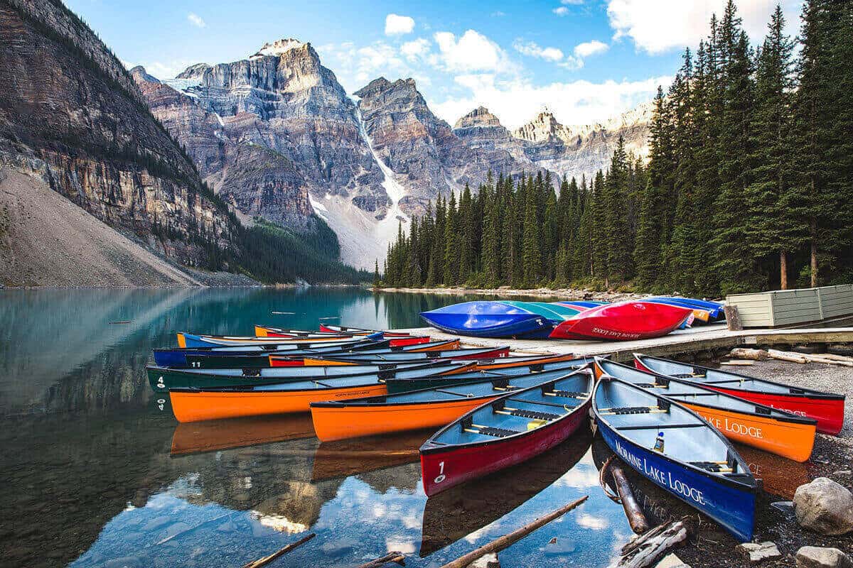 Canoes at a dock of a lake with a scenic mountain view/