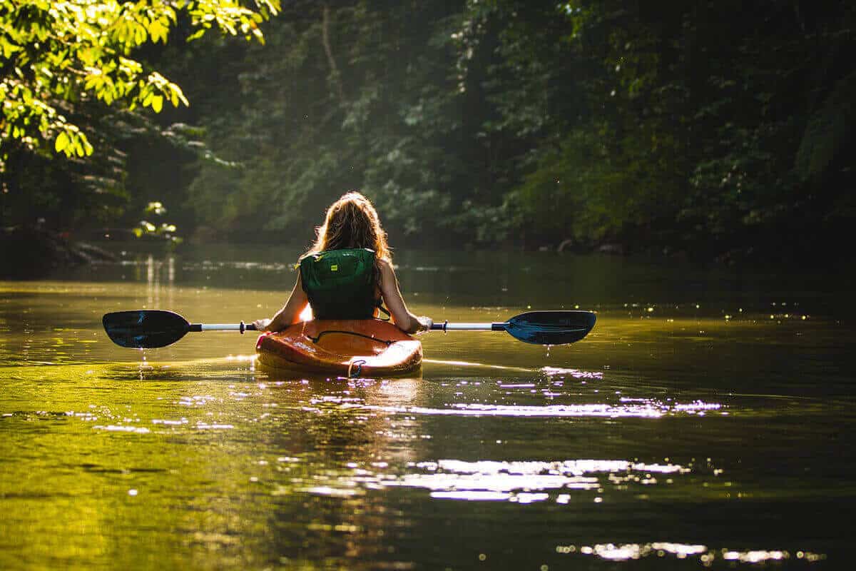 A woman kayaking on a river.