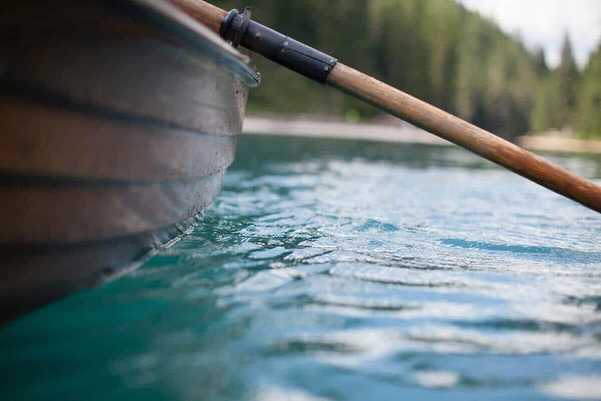 An wooden oar mounted to the side of a boat.